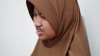 Genç Asyalı Müslüman kadın, tiksindirici bir ifadeyle, reddedilme jestleriyle ve rahatsız edici duygularla bakıyor.