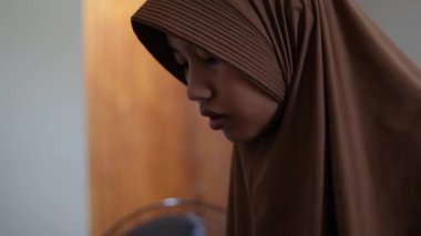 Genç Asyalı Müslüman kadın odasında tek başına yemek yiyor, yalnız yaşayan bir öğrenci. 