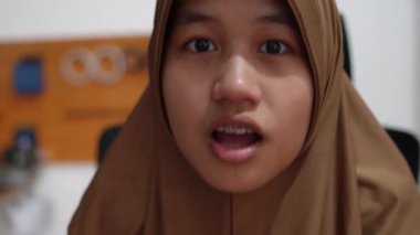 Genç Asyalı Müslüman kadın şaşırmış. Heyecanlı ifade, büyük gözler ve açık ağız. Şaşırtıcı bir jest.