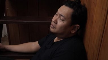 Üzgün Asyalı adam evinde merdivenlerde oturuyor, umutsuzluk hayal kırıklığı stres kaybı, hayat sorunları konsepti.