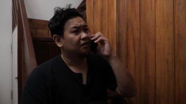 Yetişkin Asyalı adam telefonda kötü haber alıyor, üzgün üzgün ağlayan surat ifadesi