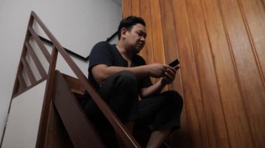 Yetişkin Asyalı adam telefonda kötü haber alıyor, üzgün üzgün ağlayan surat ifadesi