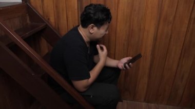 Yetişkin Asyalı adam telefonda kötü haber alıyor, üzgün üzgün ağlayan surat ifadesi