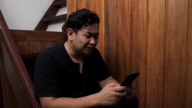 Yetişkin Asyalı adam telefonda kötü haber alıyor, üzgün üzgün ağlayan surat ifadesi