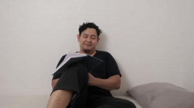 Yetişkin bir Asyalı, uyumadan önce günlüğüne günlük tutuyor, hayatını yansıtıyor.