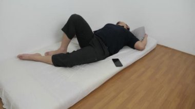 Yetişkin bir Asyalı sabah yataktan kalktıktan sonra telefonunu kontrol ediyor.