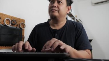 Asyalı adam evde bilgisayarında daktilo yazıyor, uzaktan çalışan serbest çalışan, online iş kavramı, ciddi endişeli ifade