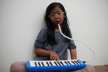 Küçük Asyalı kız piyano çalıyor, melodi org üflüyor müzik enstrümanı