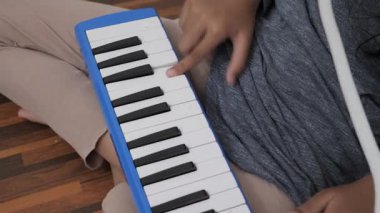 Küçük Asyalı kız piyano çalıyor, melodi org enstrümanı çalıyor