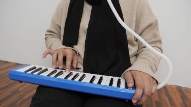 Piyanik çalan isimsiz bir kadın, melodi org enstrümanı çalıyor