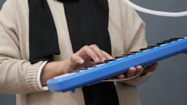 Piyanik çalan isimsiz bir kadın, melodi org enstrümanı çalıyor