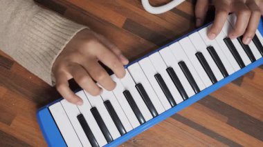 Piyanik çalan isimsiz bir kadın, melodi org enstrümanı çalıyor