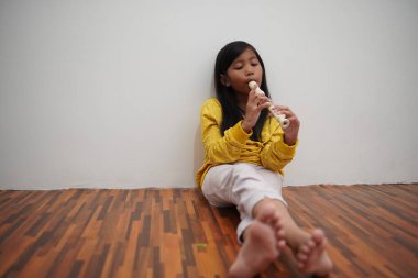 Küçük Asyalı kız flüt çalıyor, müzik aleti.