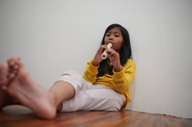 Küçük Asyalı kız flüt çalıyor, müzik aleti.