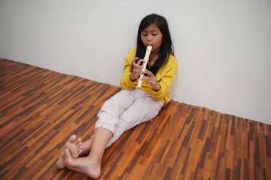 Küçük Asyalı kız flüt çalıyor, müzik aleti.