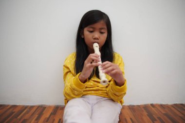 Küçük Asyalı kız flüt çalıyor, müzik aleti.