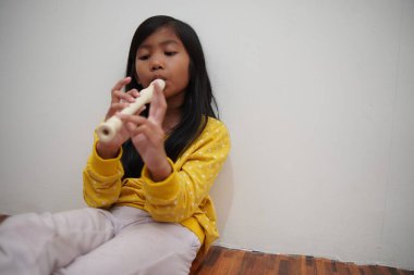 Küçük Asyalı kız flüt çalıyor, müzik aleti.