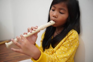 Küçük Asyalı kız flüt çalıyor, müzik aleti.