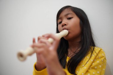 Küçük Asyalı kız flüt çalıyor, müzik aleti.