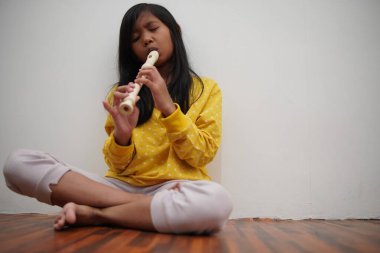 Küçük Asyalı kız flüt çalıyor, müzik aleti.