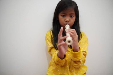 Küçük Asyalı kız flüt çalıyor, müzik aleti.