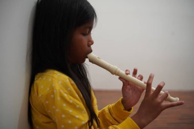 Küçük Asyalı kız flüt çalıyor, müzik aleti.