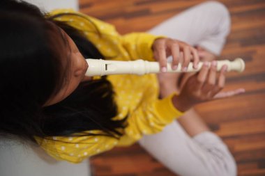 Küçük Asyalı kız flüt çalıyor, müzik aleti.