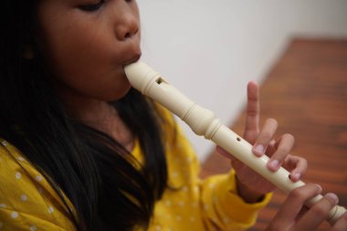 Küçük Asyalı kız flüt çalıyor, müzik aleti.