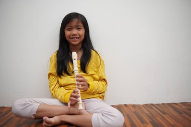 Küçük Asyalı kız flüt çalıyor, müzik aleti.