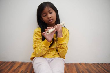 Küçük Asyalı kız flüt çalıyor, müzik aleti.