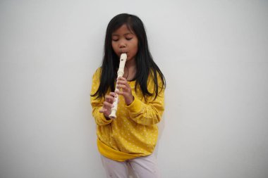 Küçük Asyalı kız flüt çalıyor, müzik aleti.