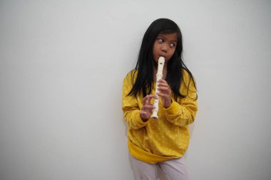 Küçük Asyalı kız flüt çalıyor, müzik aleti.