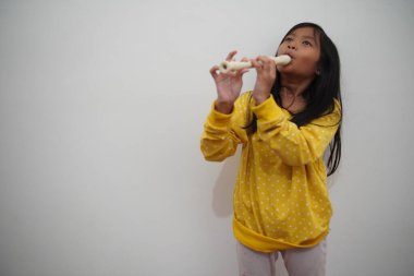 Küçük Asyalı kız flüt çalıyor, müzik aleti.