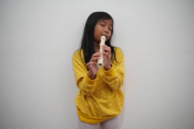 Küçük Asyalı kız flüt çalıyor, müzik aleti.