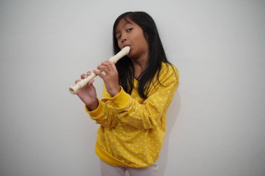 Küçük Asyalı kız flüt çalıyor, müzik aleti.