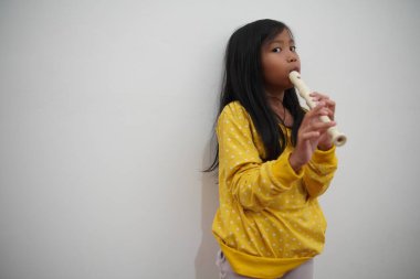 Küçük Asyalı kız flüt çalıyor, müzik aleti.