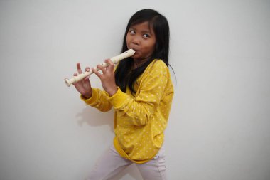 Küçük Asyalı kız flüt çalıyor, müzik aleti.