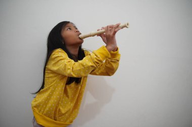 Küçük Asyalı kız flüt çalıyor, müzik aleti.