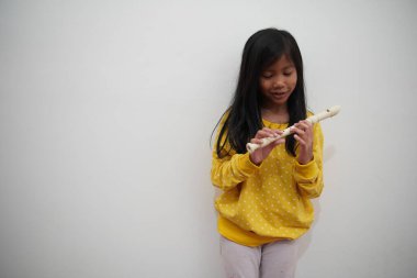 Küçük Asyalı kız flüt çalıyor, müzik aleti.