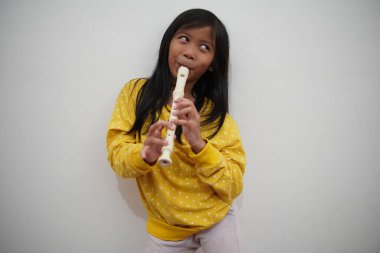 Küçük Asyalı kız flüt çalıyor, müzik aleti.