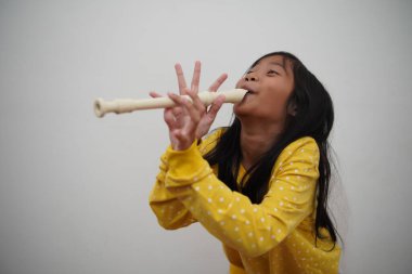 Küçük Asyalı kız flüt çalıyor, müzik aleti.