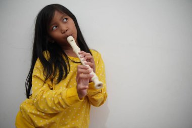 Küçük Asyalı kız flüt çalıyor, müzik aleti.