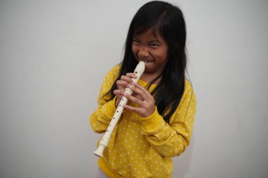 Küçük Asyalı kız flüt çalıyor, müzik aleti.