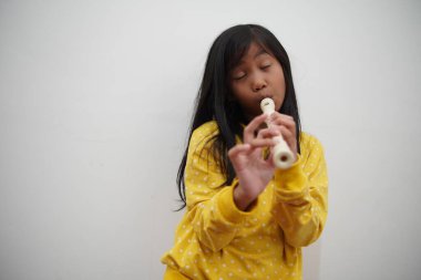 Küçük Asyalı kız flüt çalıyor, müzik aleti.