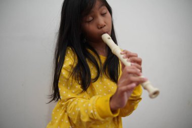 Küçük Asyalı kız flüt çalıyor, müzik aleti.