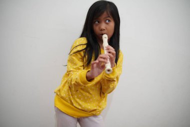 Küçük Asyalı kız flüt çalıyor, müzik aleti.