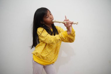 Küçük Asyalı kız flüt çalıyor, müzik aleti.