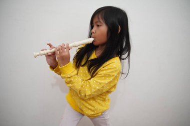 Küçük Asyalı kız flüt çalıyor, müzik aleti.
