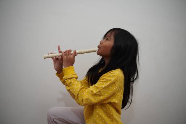 Küçük Asyalı kız flüt çalıyor, müzik aleti.