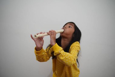 Küçük Asyalı kız flüt çalıyor, müzik aleti.